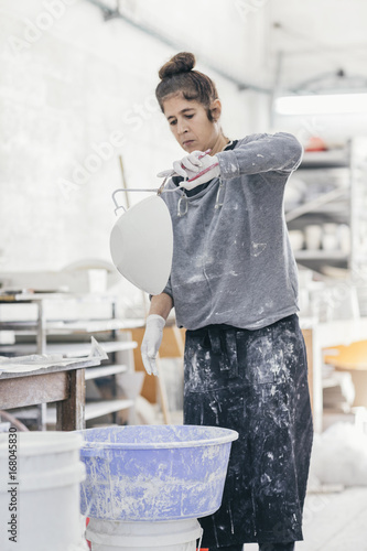 Female ceramic artist glazing a bowl in her studio