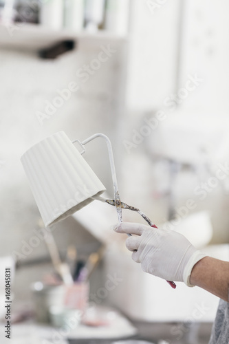 Closeup of a hand holding a clamp with a ceramic cup