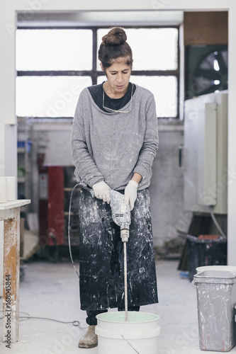 Female ceramic artisan using power tool to blend material