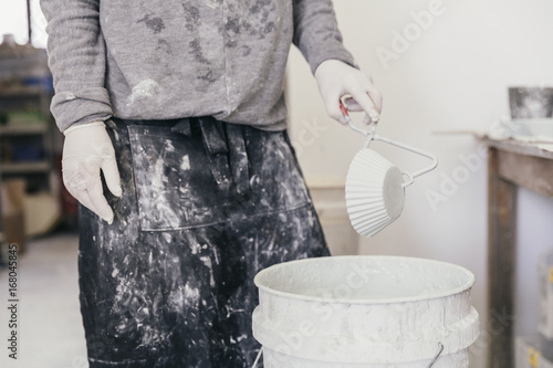 Person holding clamps glazing a ceramic bowl