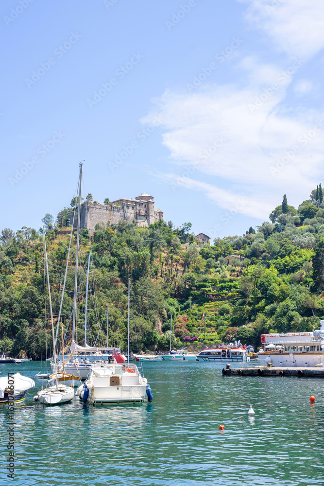 Daylight view to beauties of Portofino, Italy. Ships on water with people resting in them.