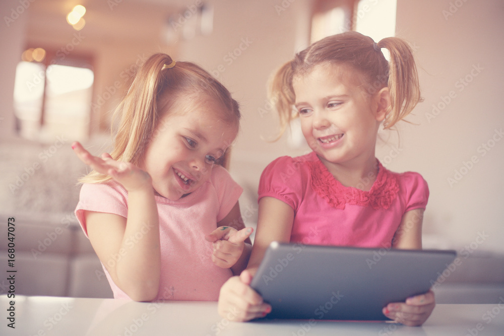 Two little sisters using tablet. Two little sisters using tablet.