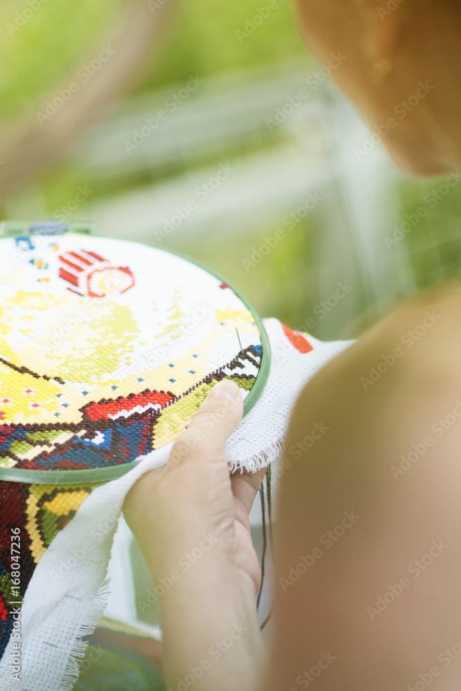 Fototapeta premium Hands of a woman, cross-stitch, close-up