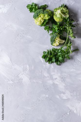 Fresh uncooked parsley and broccoli on gray concrete background. Flat lay with copy space. Clear food background