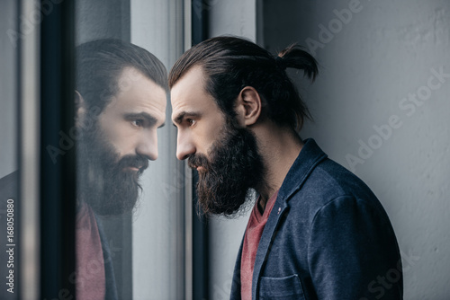 man looking at reflection in glass photo