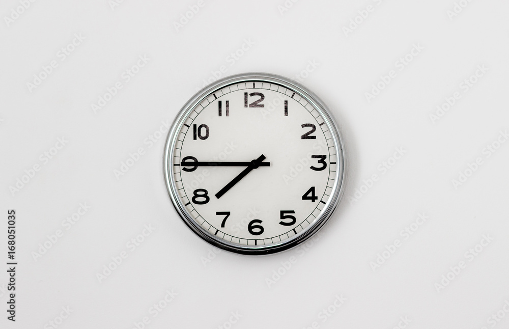 White Clock hanging on a white wall showing time 7:45 White Clock hanging on a white wall showing time 7:45