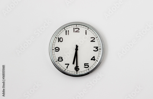 White Clock hanging on a white wall showing time 6:30