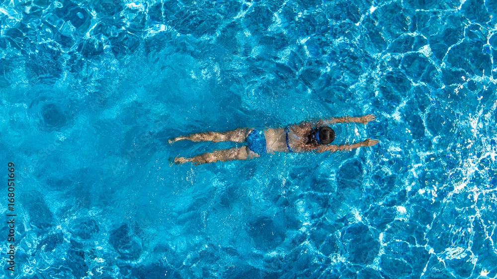 Aerial top view of woman in swimming pool water from above, tropical vacation holiday concept
