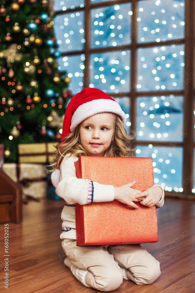 Little cute girl with gift box near christmas tree Little cute girl with gift box near christmas tree