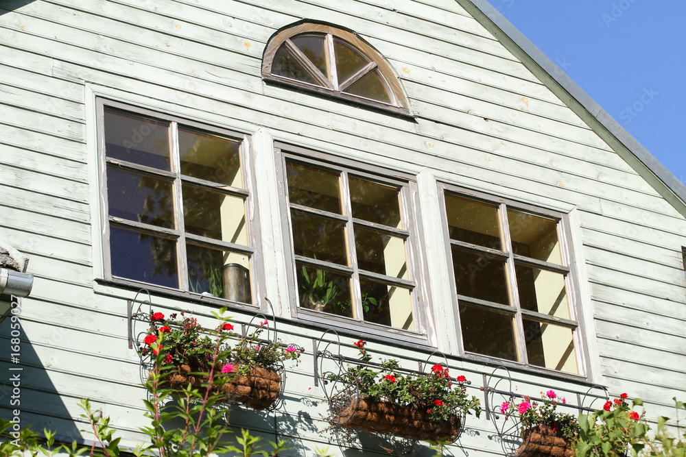 Wood house windows with flowers under them.