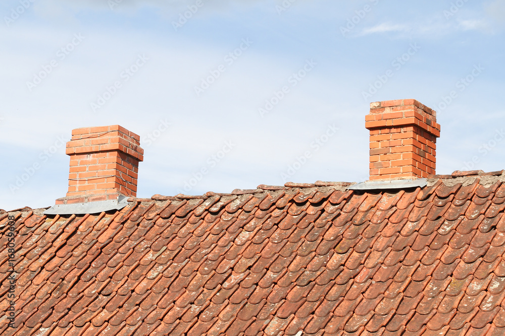 Naklejka premium Countryside view of two small chimneys on rooftop.