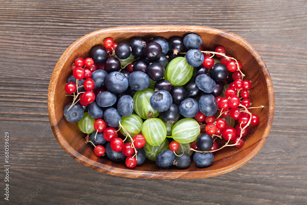 Red black currant blueberry gooseberry in a wooden bowl Red black currant blueberry gooseberry in a wooden bowl