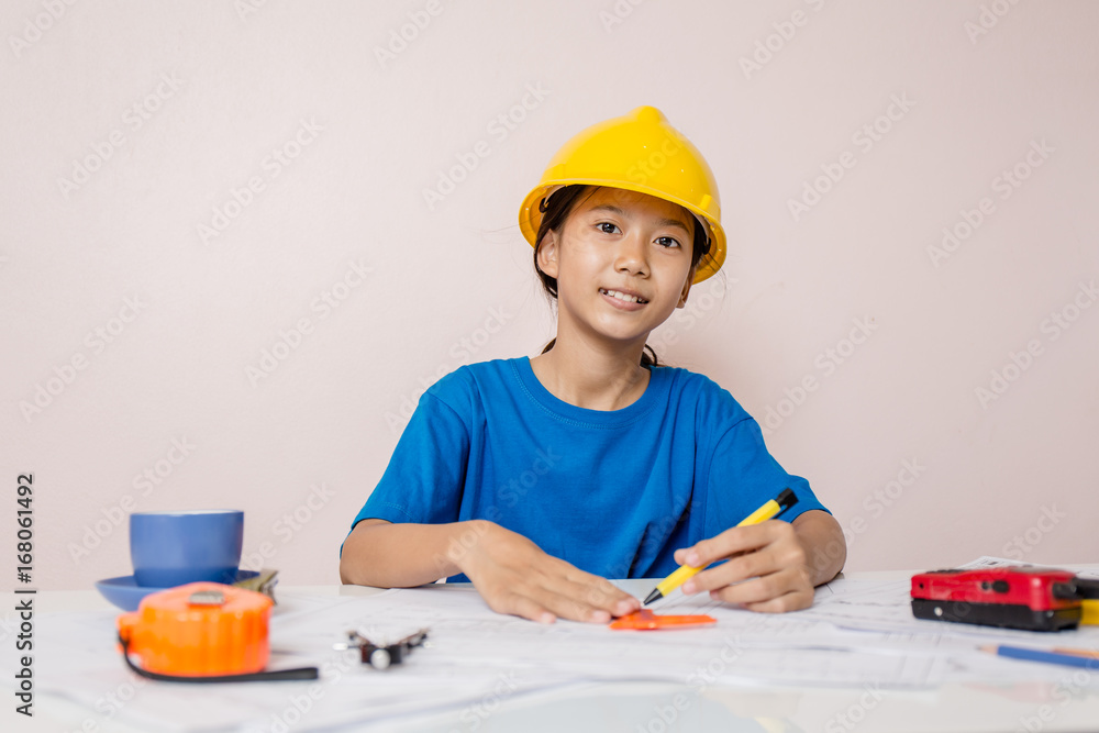 Asian girl child playing as an engineer the building layout and helmet are smiling and happy on weekends. Asian girl child playing as an engineer the building layout and helmet are smiling and happy on weekends.