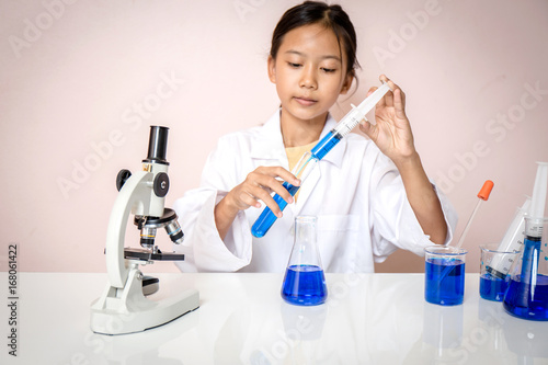 Asian girl playing as a scientist to experiment with laboratory equipment and microscope cameras in scientific laboratory.