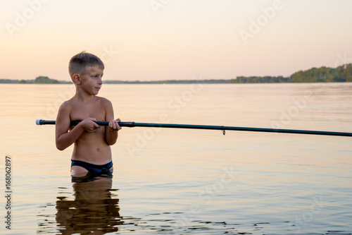 Quadro su tela Boy fishing waist deep in water