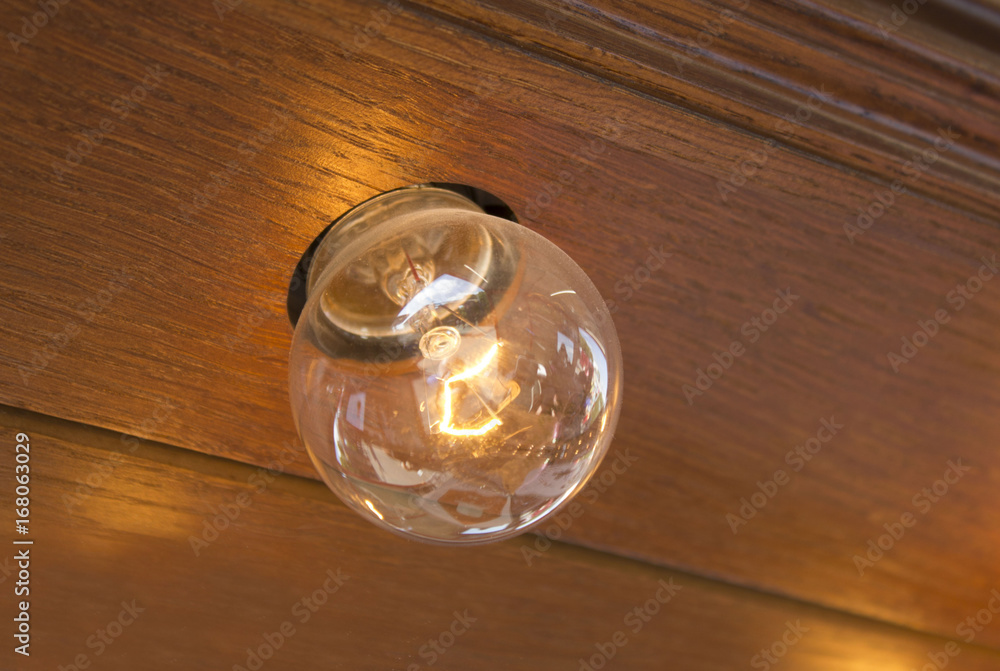 The old light bulb burns on the wooden wall