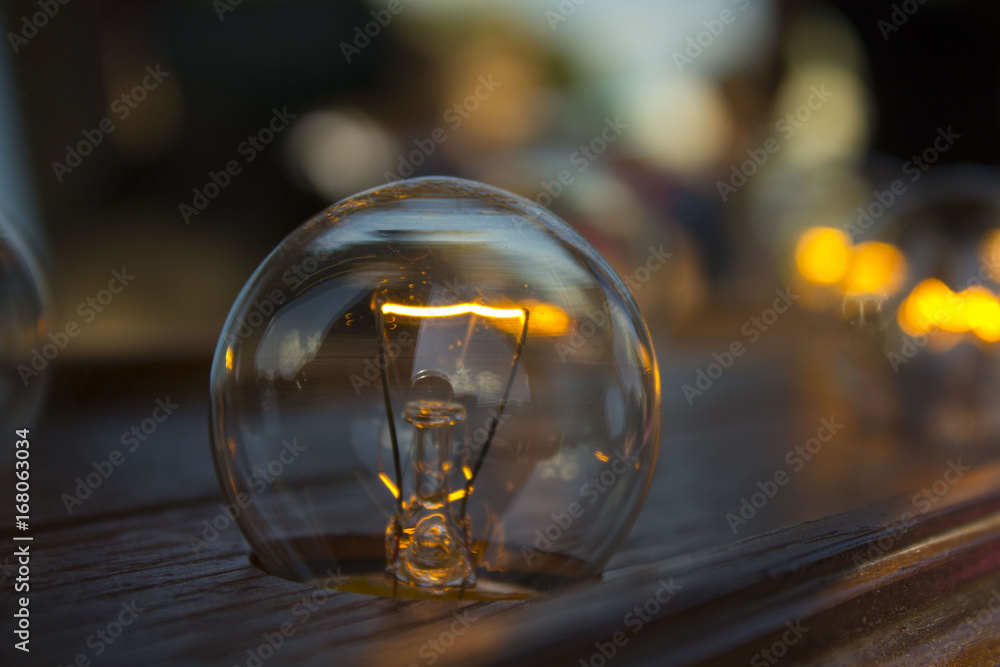 The old light bulb burns on the wooden wall The old light bulb burns on the wooden wall