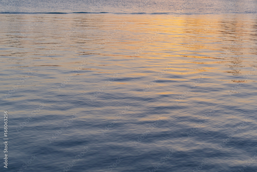 Close-up of seawater with reflection of golden sunset, texture, background. Meditation concept.