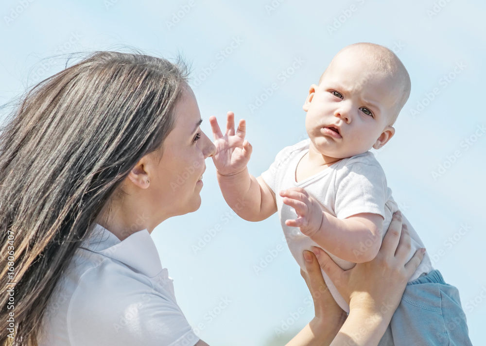 Portrait of a small newborn baby boy and his mother throwing him up to blue sky iat sunny summer day Portrait of a small newborn baby boy and his mother throwing him up to blue sky iat sunny summer day