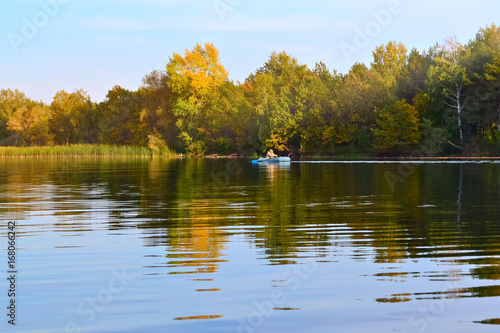 Autumn river landscape with a boat in the distance