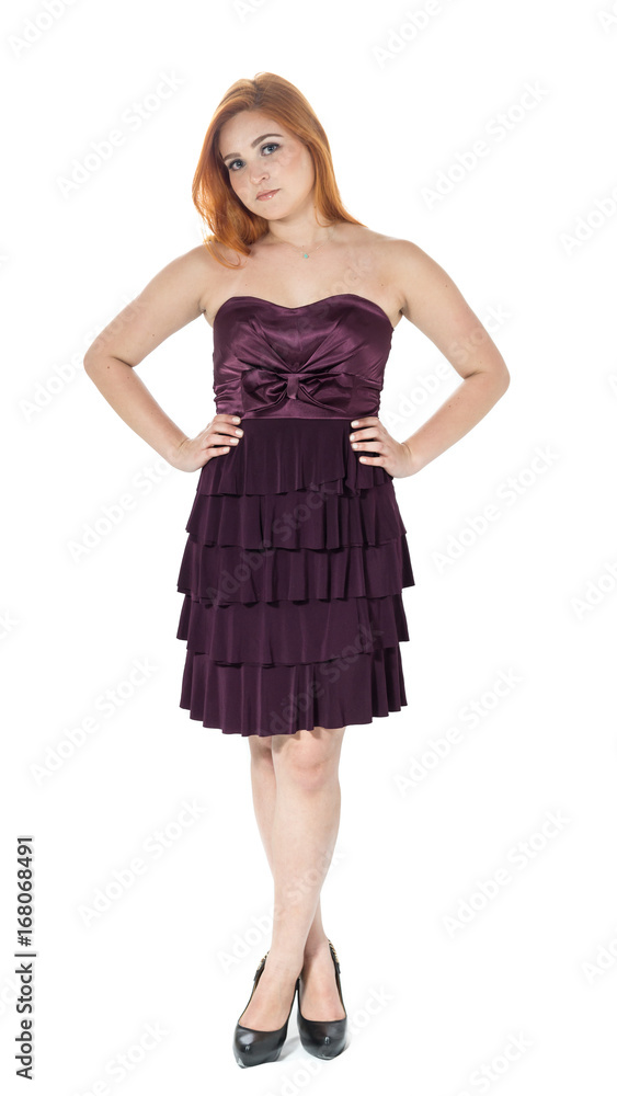 Girl is standing and legs are crossed. Pose for the picture. Redheaded girl wearing dark purple strapless dress.