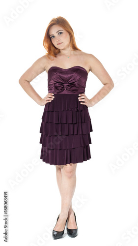 Girl is standing and legs are crossed. Pose for the picture. Redheaded girl wearing dark purple strapless dress.