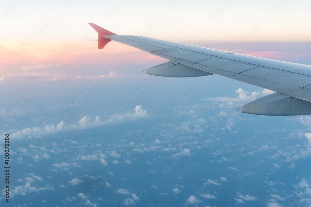Airplane wing from window seat at sunset with clouds. Airplane wing from window seat at sunset with clouds.