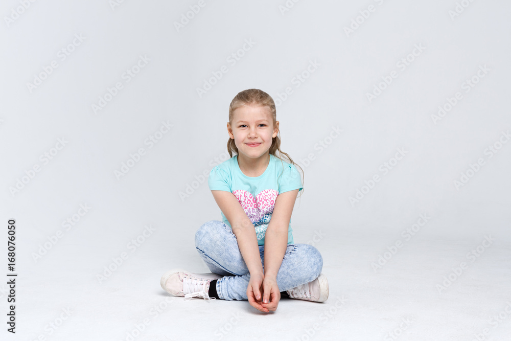 Portrait of a cute girl sitting on the floor on white background Portrait of a cute girl sitting on the floor on white background