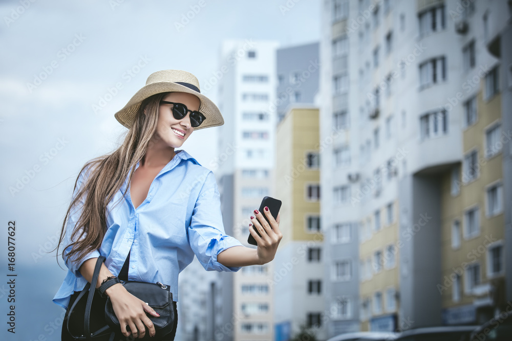 Young beautiful woman model lady fancy shirt and hat with a mobile phone on a city street