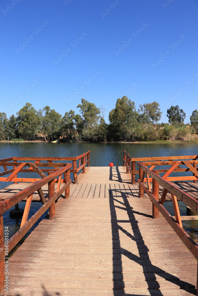 wooden pier on big lake surrounded by trees wooden pier on big lake surrounded by trees