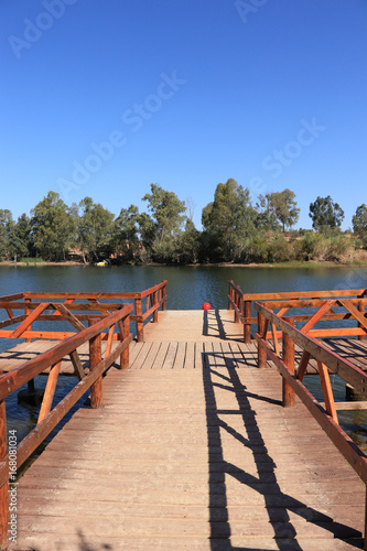 wooden pier on big lake surrounded by trees © nvphoto