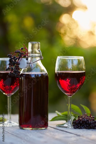 Glasses of elderberry wine and elderberries on wooden table