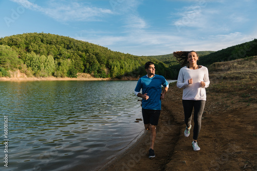 Fitness enthusiasts smiling and having a nice time training by the lake