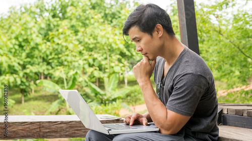 Asian man using a laptop on the balcony.