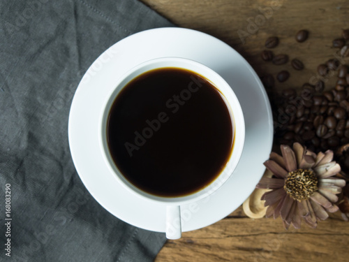 Place the cup on fabric. Wooden table with coffee beans