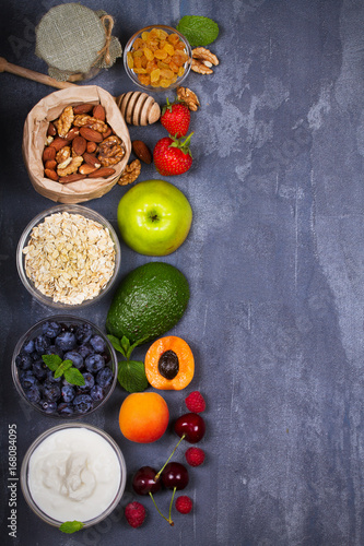 Yogurt, Oat Flakes, Fruits, Honey and Summer Berries. View from above, top studio shot of fruit background. Flat lay setup made of selection of healthy food, copy space, overhead