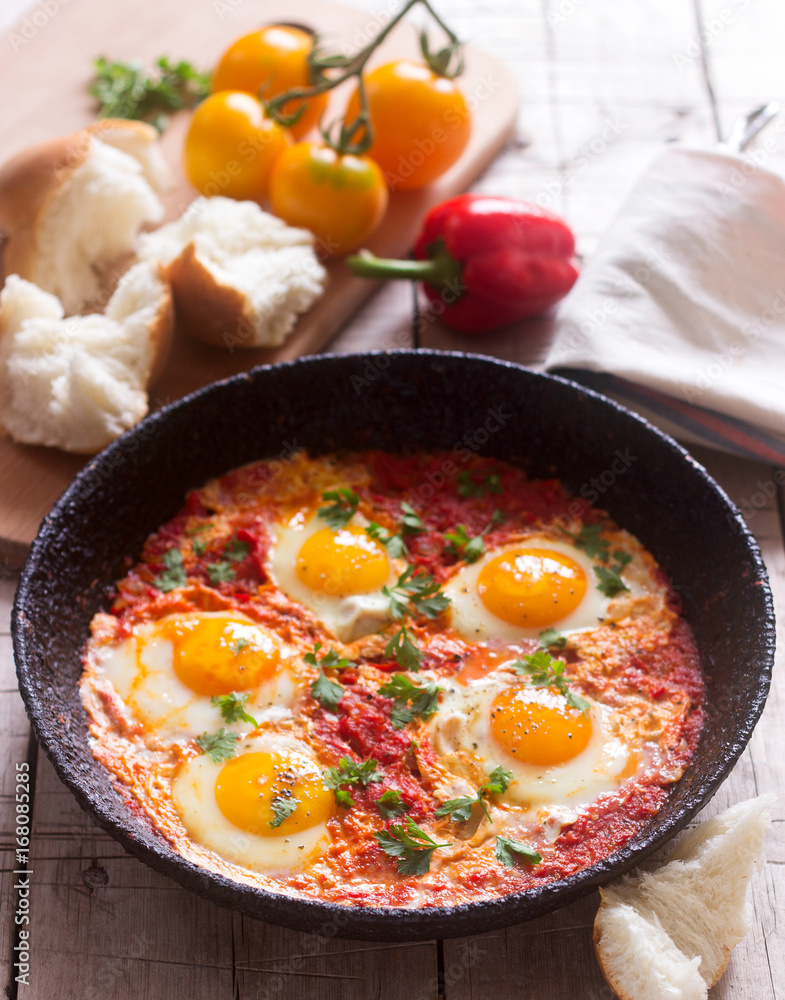 Shakshuka with bread on a wooden table. Middle eastern traditional dish. Homemade. Selective focus. Shakshuka with bread on a wooden table. Middle eastern traditional dish. Homemade. Selective focus.