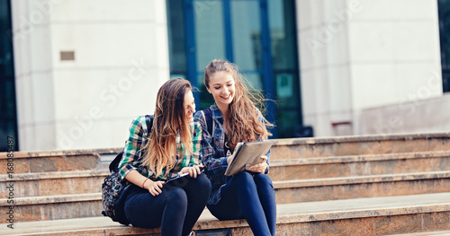 Teen girls engaged in happy conversation meeting together in the bright pleasant morning.Girls sharing their vacation stories on the first day of school. Student girls back to school university stairs