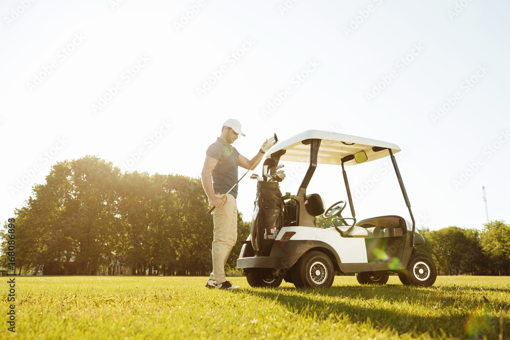 Golfer taking clubs from a bag in a golf cart