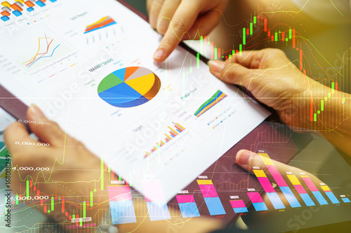 business women hand holding business analysis document while colleague point finger on pie chart with great teamwork collaborative cooperation during discussion in meeting mixed stock market graph