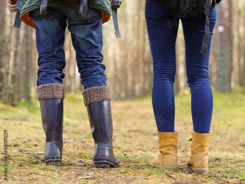 Close-up image of legs of a couple walking in forest. Camp, tourism, hiking concept.