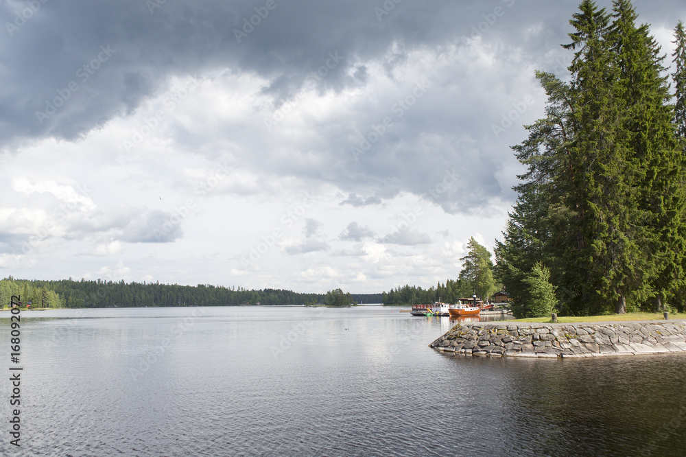 Lakeside view in Finland during summer. Stormy clouds in the sky. Green forests.