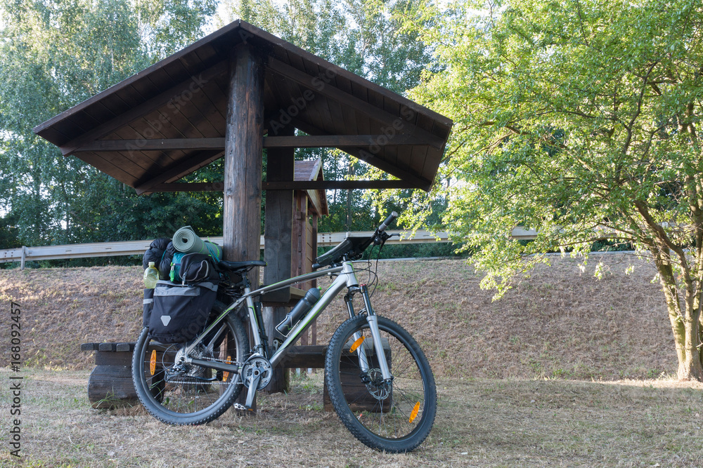 Mountain bike with saddlebags round the wooden arbour Mountain bike with saddlebags round the wooden arbour