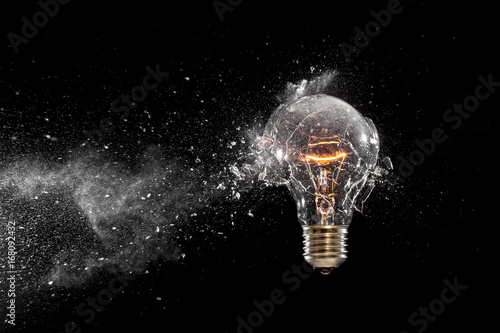 breaking a glass bulb black background.creativity  fragility  time instant