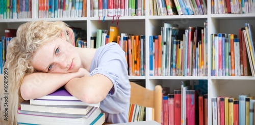 Composite image of tired teeenager sleeping in a library