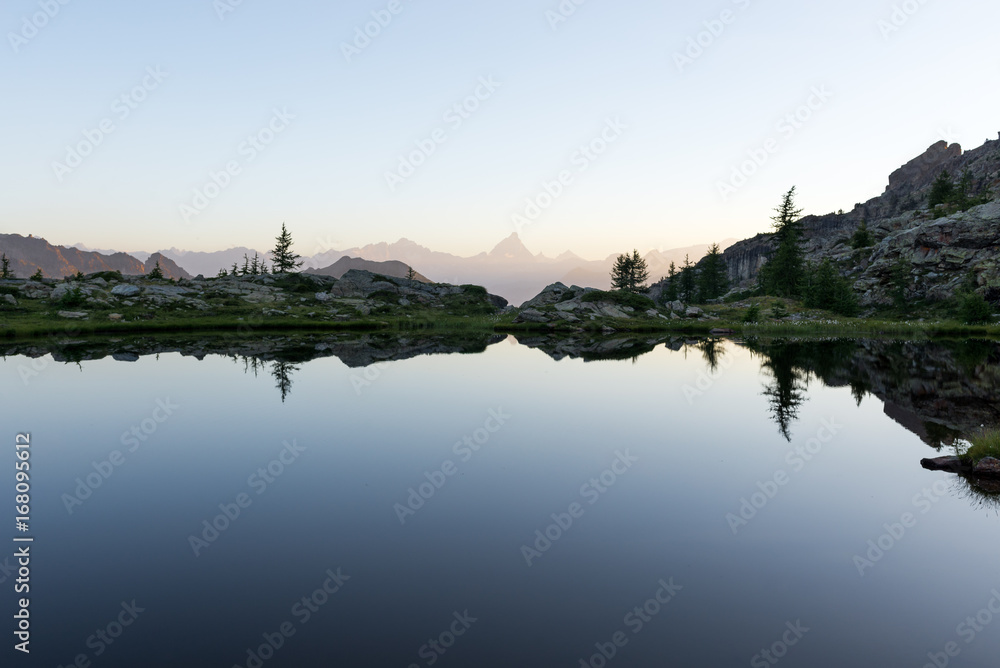 Fototapeta premium Mountain lake reflection at dawn in summer outdoor.