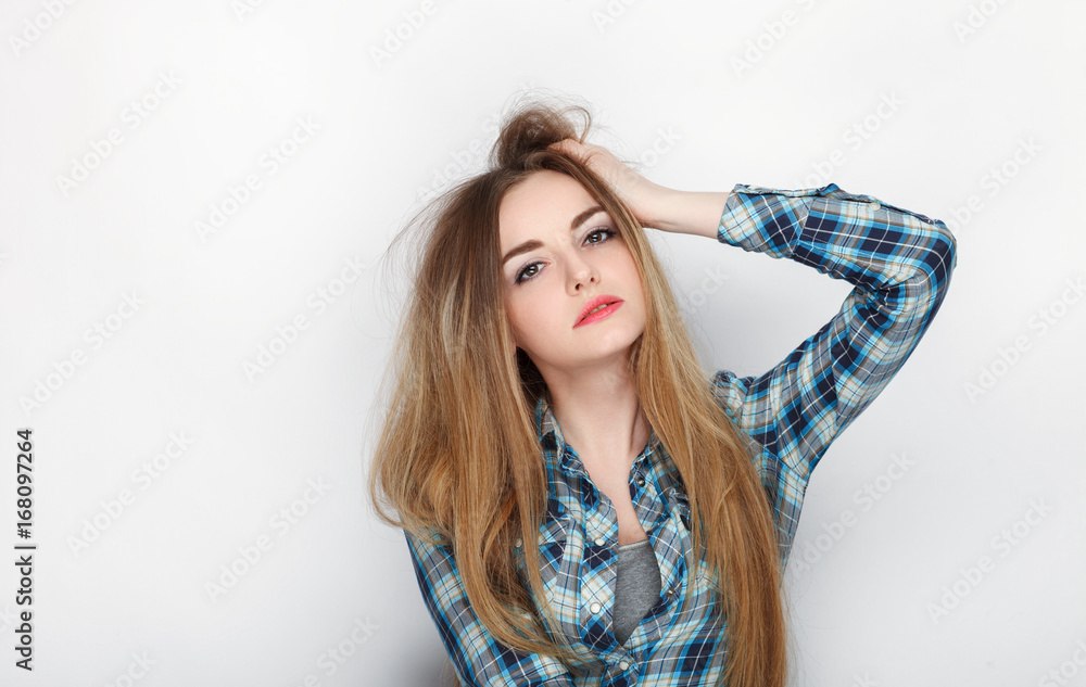 Beauty portrait of young adorable fresh looking blonde woman with hair chaos in blue plaid shirt. Emotion and facial expression concept. Beauty portrait of young adorable fresh looking blonde woman with hair chaos in blue plaid shirt. Emotion and facial expression concept.