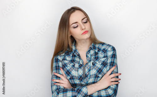 Beauty portrait of young adorable fresh looking blonde woman with crossed hands hair chaos in blue plaid shirt. Emotion and facial expression concept.