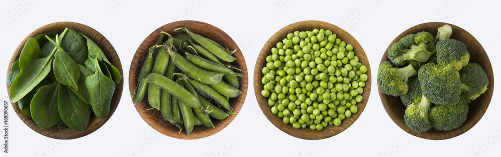 Broccoli, green peas and spinach in wooden bowl. Top view. Vegetables isolated on a white background. Broccoli, green peas and spinach in wooden bowl. Top view. Vegetables isolated on a white background.