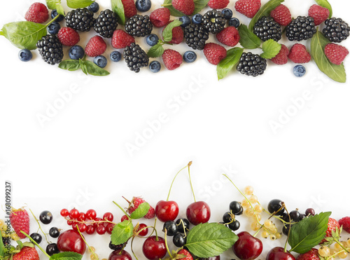 Ripe raspberries, blueberries, blackberries, redcurrants, blackcurrants, mulberries and cherries on white background. Berries at border of image with copy space for text. 